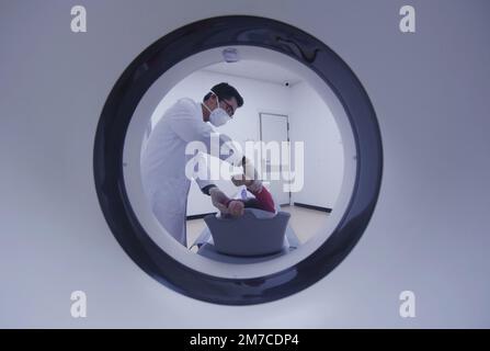 HANGZHOU, CHINA - JANUARY 9, 2023 - A radiologist at a community health Service center helps a citizen lie flat on a CT machine in Hangzhou, Zhejiang Stock Photo