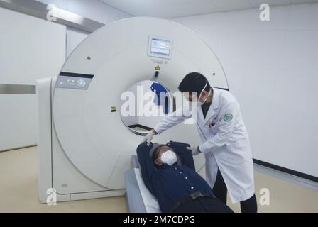 HANGZHOU, CHINA - JANUARY 9, 2023 - A radiologist at a community health Service center helps a citizen lie flat on a CT machine in Hangzhou, Zhejiang Stock Photo