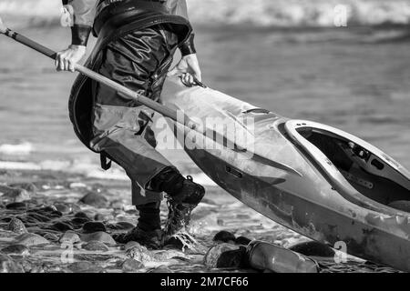 Kayaker pulling his boat along a shore Stock Photo