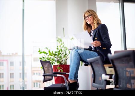 Confident middle aged businesswoman making a video call on her laptop at the office. Stock Photo