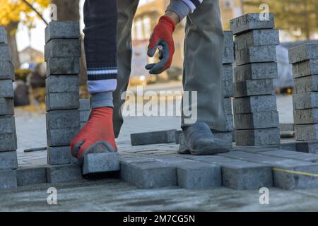 In house courtyard master is laying gray concrete paving brick slabs on top sand foundation base for paving bricks. Stock Photo