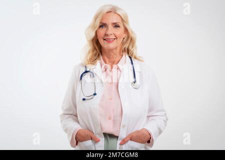 Studio shot of smiling female doctor. Confident healthcare worker is wearing lab coat and stethoscope. She is against white background. Copy space. Stock Photo