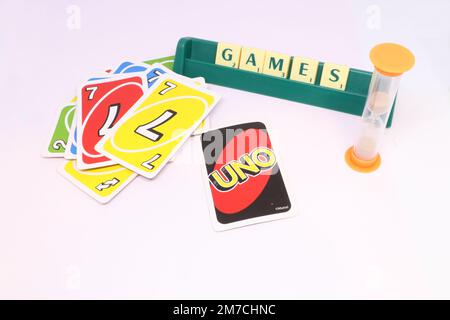 A concept of a games night showing the word 'games' spelled in scrabble tiles on a tile rack. UNO cards are spread out in a pile with a sand timer. Stock Photo