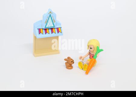 a lego mini figure girl holding a carrot feeding a pet bunny by a building with bunting on Stock Photo