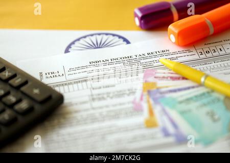 KYIV, UKRAINE - MAY 4, 2022 Indian income tax return blank form with pen and indian rupees bills on indian country flag close up. Annual tax report concept Stock Photo