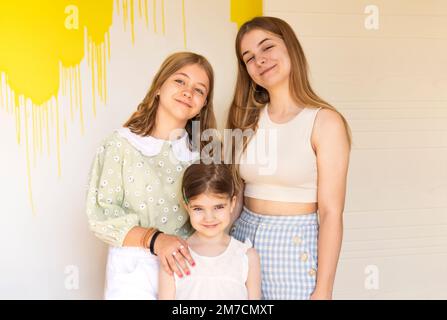 Three sisters of different ages have fun at home, hugging together. Laugh, hug, express positive emotions and feelings Stock Photo