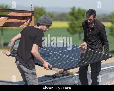 Male team engineers installing stand-alone solar photovoltaic panel ...