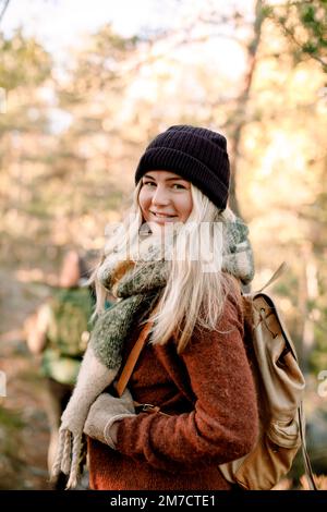 Side view of smiling young woman with backpack in forest Stock Photo