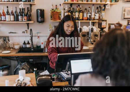 Smiling young female owner taking order from customer in cafe Stock Photo
