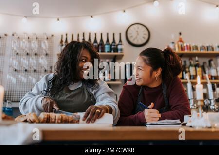 Happy female owner discussing with coworker at table in cafe Stock Photo