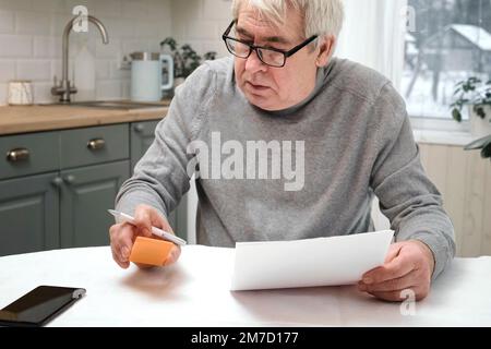 Senior Man Checking Calculating Personal Finance at Home, Feeling Stress from Money Problem. Concerned Elderly Male get Official Bank Notification, Fi Stock Photo