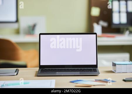 Background image of open laptop with white screen mock up on desk in cozy office setting, copy space Stock Photo