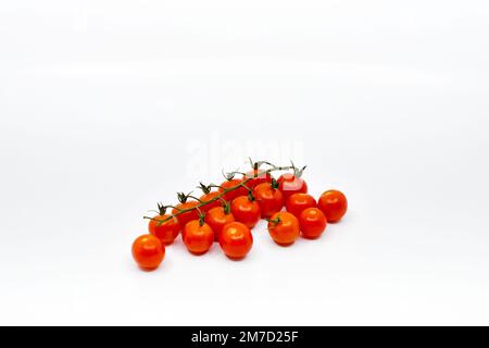 Cherry tomatoes on the vine on a plain white background. Copy space. No people. Stock Photo