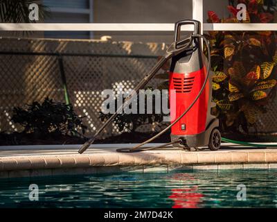 Electric powered pressure washer on swimming pool deck. Power wash cleaning service equipment. Stock Photo