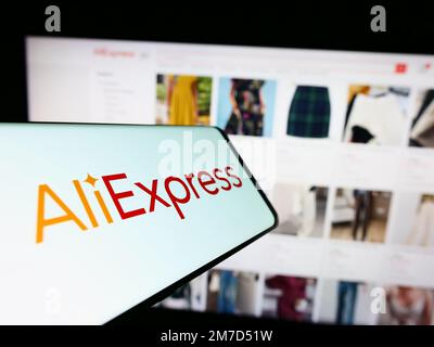 Mobile phone with logo of Chinese c-commerce company AliExpress on screen in front of business website. Focus on center of phone display. Stock Photo