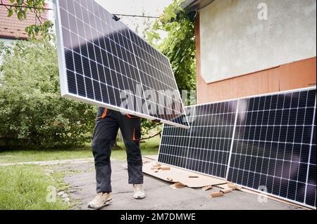 Worker holding and carrying solar panel for installing. Motion blur. Stock Photo