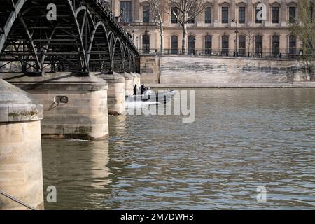 The River Seine in Paris and the river police passing by, the Pont des Arts, the Louvre in the background Stock Photo