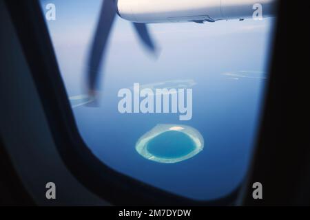 View from turboprop airplane window in Maldives. Indian Ocean with beautiful tropical islands at idyllic sunny day. Stock Photo