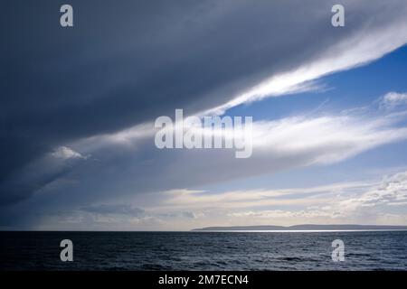 Large clouds on a strom front rolling in across ablue sky blocking the blue sky behind. Stock Photo