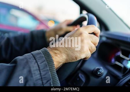 Man's hands taking the wheel of the car and driving at sunset Stock Photo