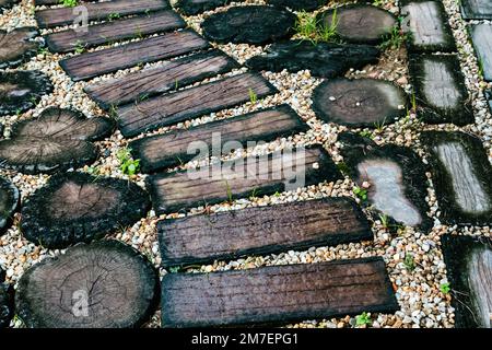 Top view of artificial wooden plate walkway made from concrete on pebble and green grass in the garden. Path in the park. Artificial wood pattern used Stock Photo