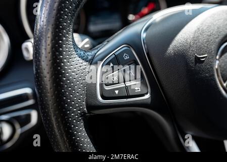 Leather multifunction steering wheel in a luxury car, visible buttons for navigation in the on-board computer, on the left. Stock Photo