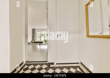 a hallway with black and white checkered flooring, mirror on the wall and an ornate gold framed mirror Stock Photo