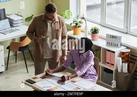 High angle view at two smiling designers choosing color swatches while working on UX project in office Stock Photo