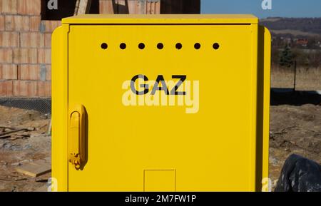 Yellow metal gas connection box at the construction site of new house. Unfinished home building under construction in Poland. Stock Photo