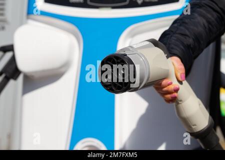 Female hand holding fast charging socket CHAdeMO. Connector plug for electric vehicles battery at EV car charging station, direct current DC. Stock Photo