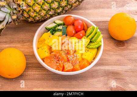 A wonderful salmon poke bowl with mango, Mexican avocado, cherry tomatoes, white rice and cucumbers Stock Photo