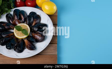 Turkish Street Flavors Stuffed Mussels With Lemon On Blue Background and Copy Space. Black Shellfish For Banner, Catalog or Menu. Stock Photo