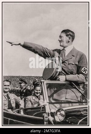 Adolf Hitler wearing a swastika armband at a 1930’s Nazi Party Nuremberg rally, with Rudolf Hess sitting behind, standing in the front of his open top Mercedes motorcar saluting the passing troops of the NSDAP political party military wing Hitler Nuremberg Rally Heil Hitler salute s Nazi Gemany 1930s Stock Photo