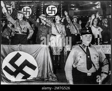 Adolf Hitler in SA uniform takes the Heil Hitler salute from his fellow Nazis at a meeting of the 'Steel Helmets' at Sports Palace in Berlin.  Also present are Prince August Wilhelm son of the former Kaiser, Frau Magda Goebbels & Doctor Wilhelm Frick September 1932: Stock Photo