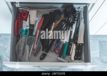 Top view of a kitchen drawer full of utensils. Concept of minimalism, tidying and cleaning. Stock Photo