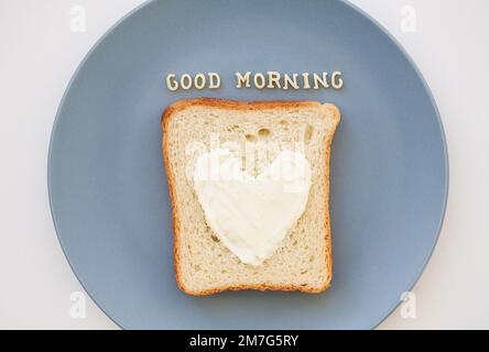 sandwich for breakfast in form of heart with cheese on a blue plate inscription good morning Stock Photo