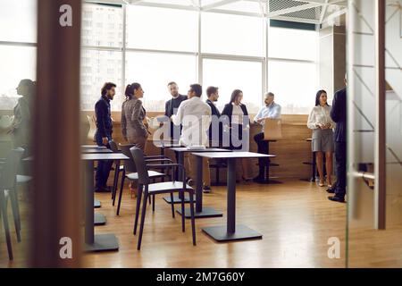Office workers communicate with each other while having casual conversations during work break. Stock Photo