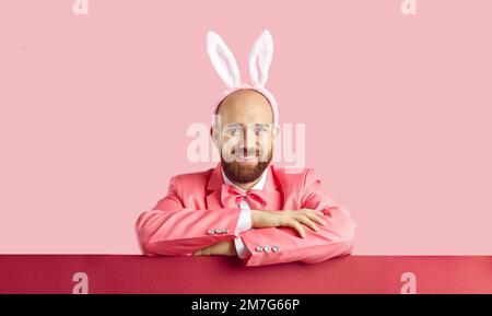 Studio portrait of cheerful handsome man wearing pink suit and Easter bunny ears Stock Photo