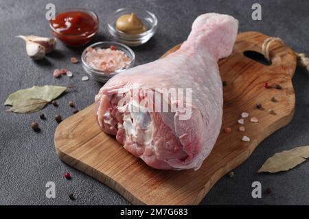 Raw turkey drumstick on a wooden board, as well as spices and seasonings Stock Photo