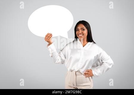 Happy confident millennial black businesswoman in white blouse hold abstract bubble, cloud for words and thoughts Stock Photo