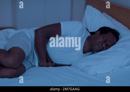 Nocturnal Panic Attack. Stressed Black Man Lying In Bed In The Night Stock Photo