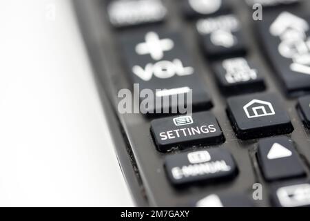 Close-up of a TV remote control with focus on the settings button Stock Photo