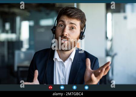 Businessman making video call from office, wearing headphones and talking to webcamera, pov screenshot Stock Photo