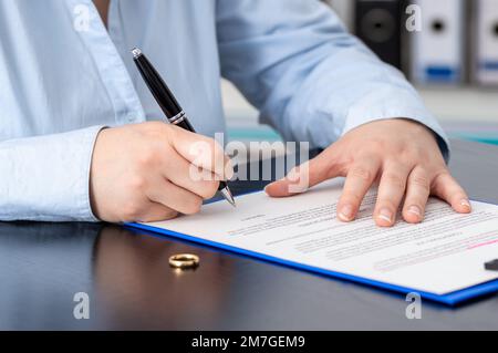 Close up of a woman's hand writing or signing a divorce document in the lawyer's office Stock Photo