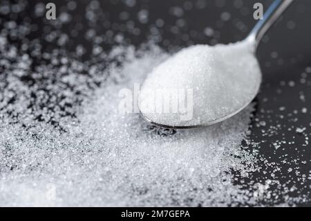 Close-up of spoon with sugar on the black table Stock Photo