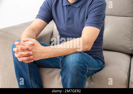 Cropped portrait of a handsome middle-aged man sitting in the living room of his house with a worried gesture while sitting on a couch in his living r Stock Photo
