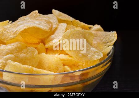 Crispy potato chips in white bowl with black background Stock Photo