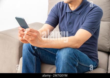 Shot of a young man using a smartphone on the sofa at home Stock Photo
