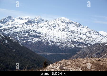 The scenic view through the train window traveling in White Pass through Boundary Ranges of the Coast Mountains reaching 873 meters altitude (Alaska). Stock Photo