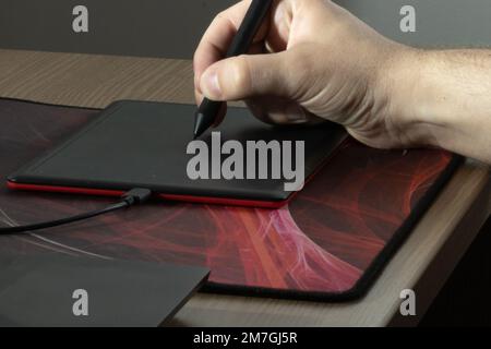 Graphic designer using a pen on a digital tablet. Stock Photo